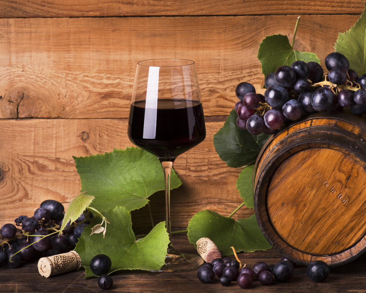 Бокал красного вина  на столе с виноградом и бочкой
