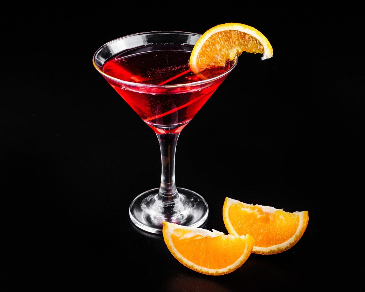 Алкогольный коктейль с кусочками апельсина на черном фоне