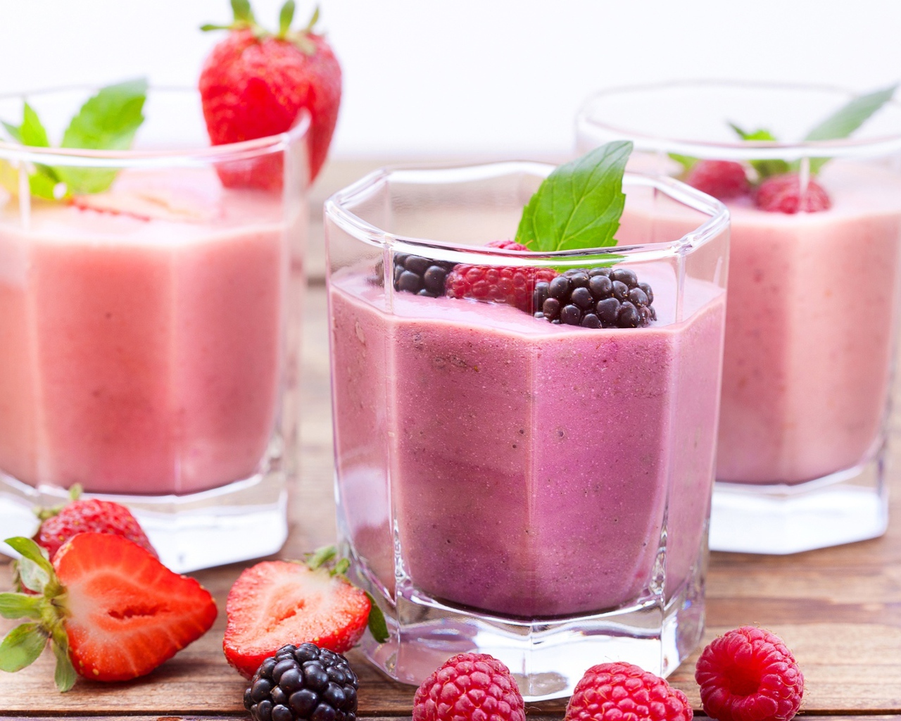 Ягодное смузи в стаканах на столе с ягодами малины, черники и клубники