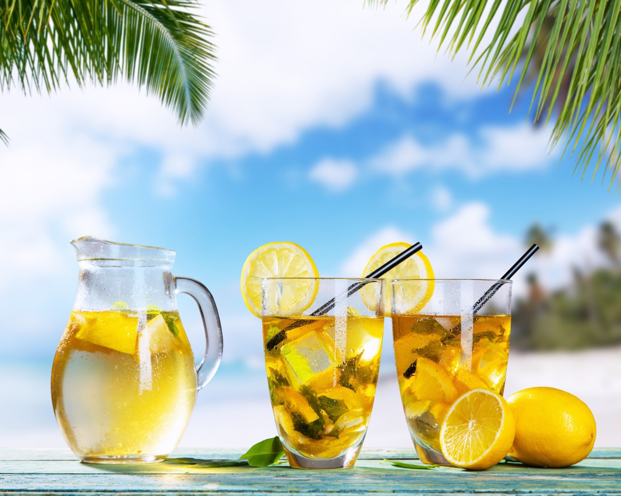 Графин и два стакана лимонада на столе на тропическом пляже