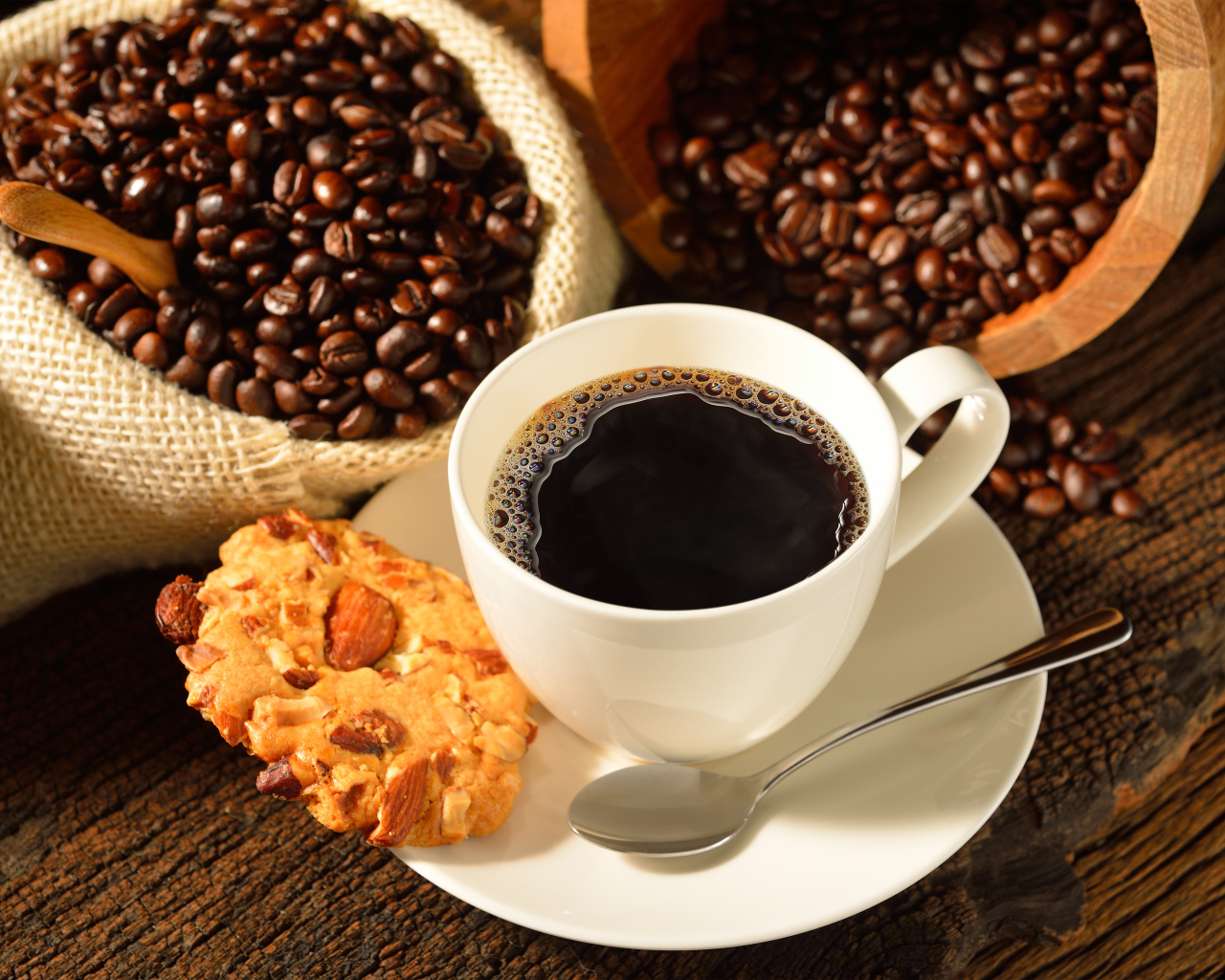 Кофейные зерна на столе с белой чашкой и печеньем