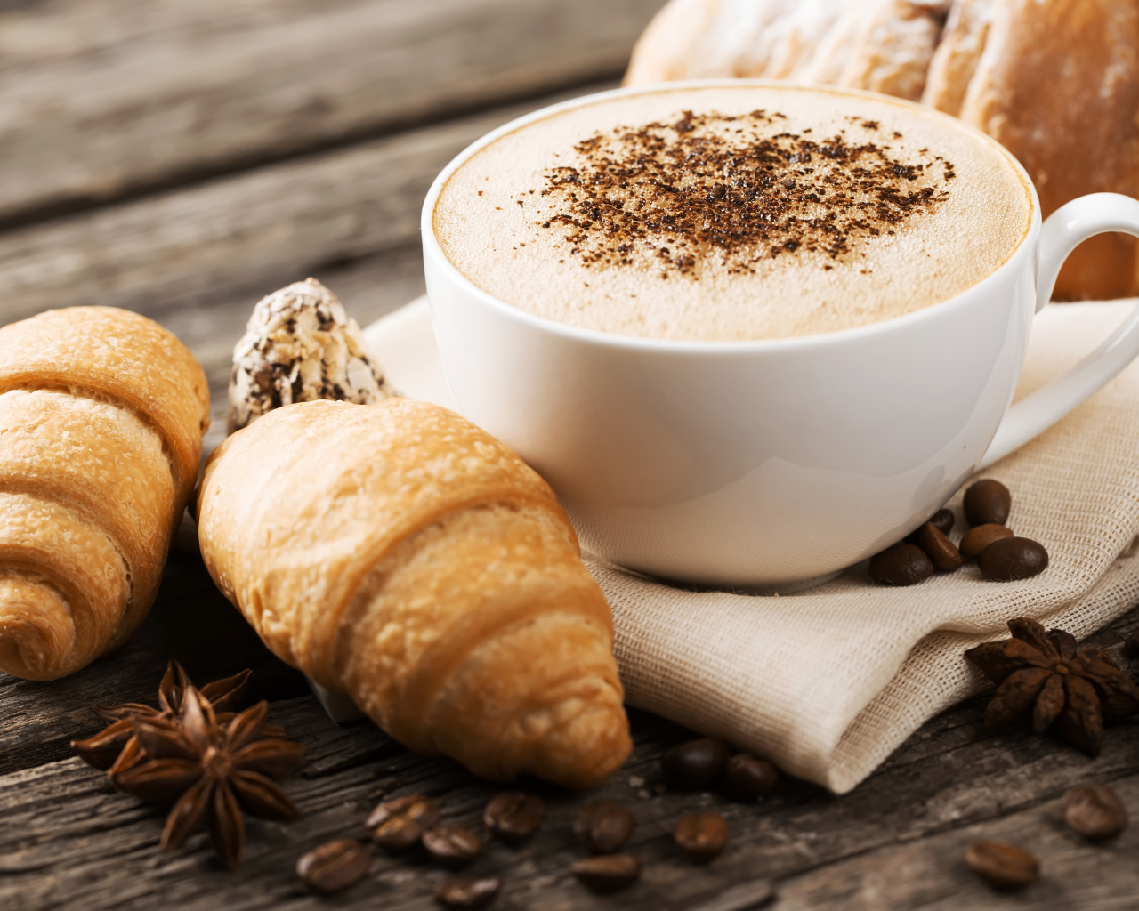 Чашка капучино на столе круассанами