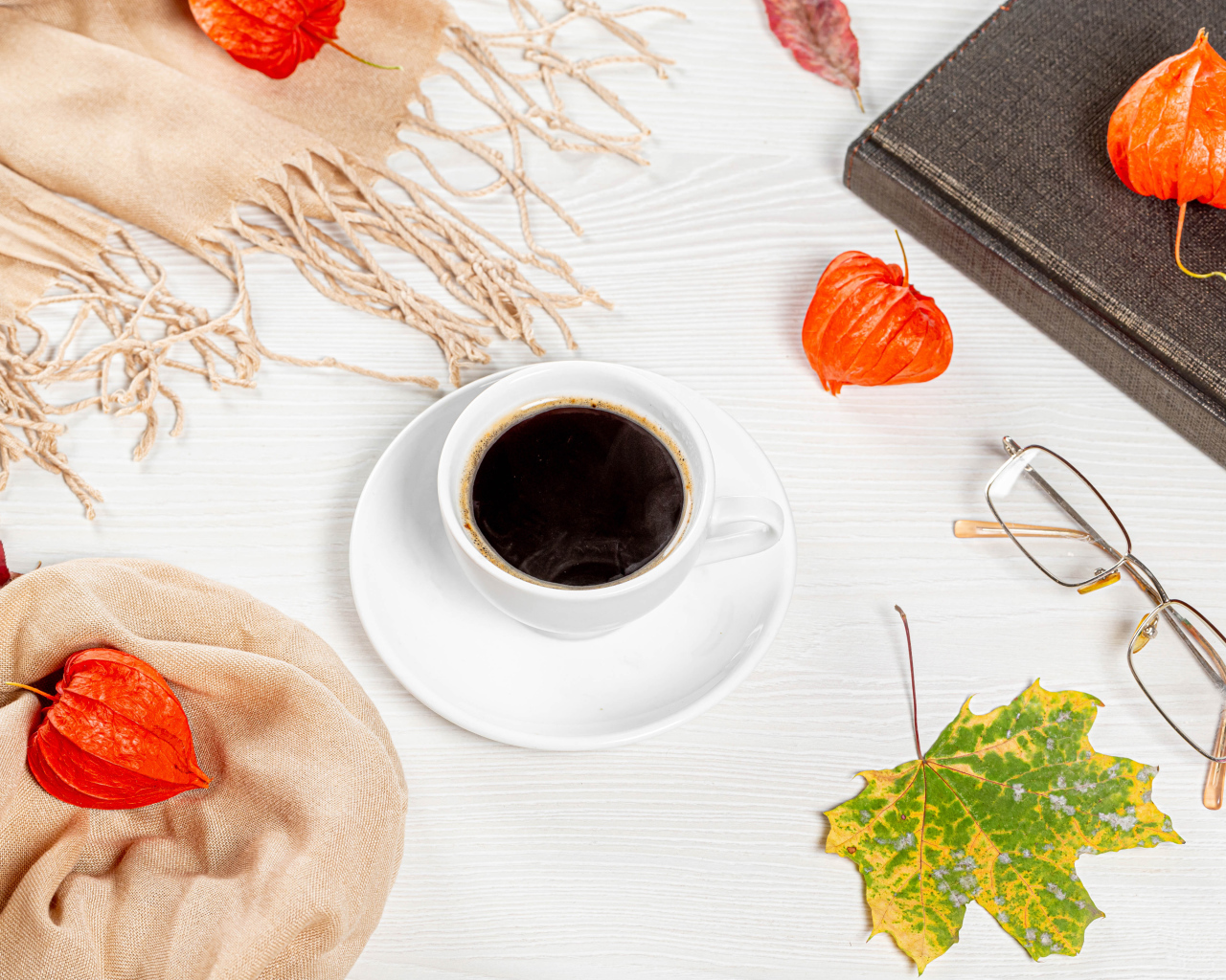 Чашка кофе на столе с книгой, очками и физалисом