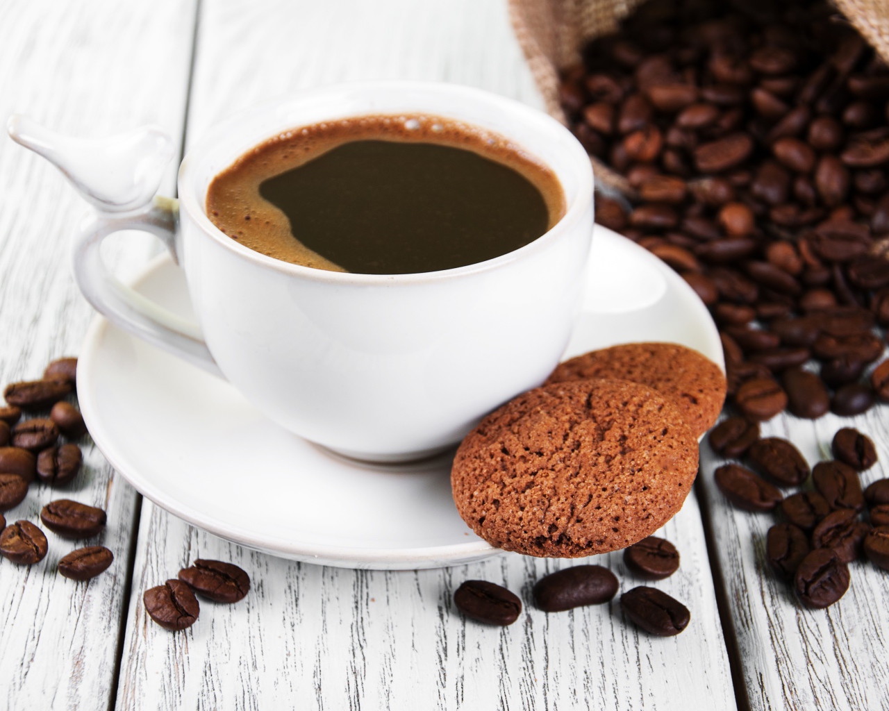 Чашка кофе на столе с кофейными зернами и печеньем