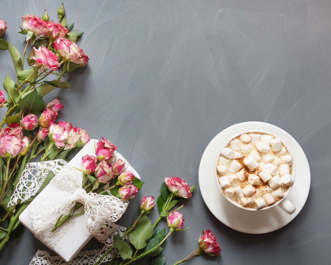 Чашка кофе с маршмеллоу на столе с подарком и букетом роз