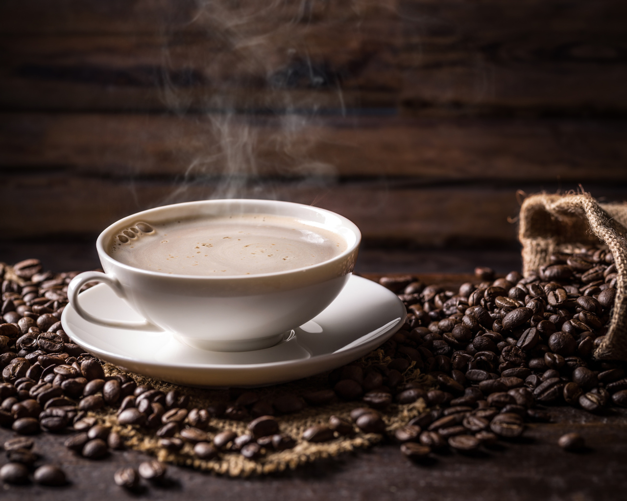 Чашка горячего ароматного кофе на столе с зернами