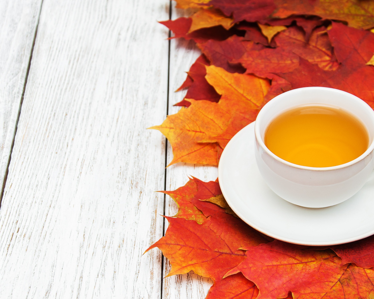 Чашка чая на столе с осенней листвой 