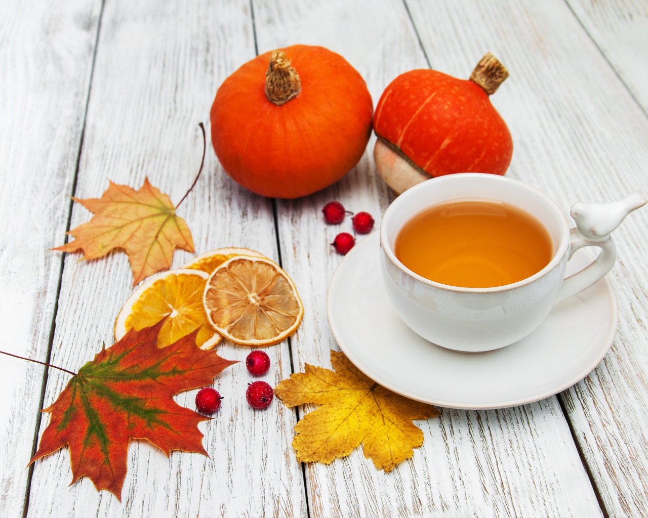 Чашка чая на столе с опавшими листьями и тыквой