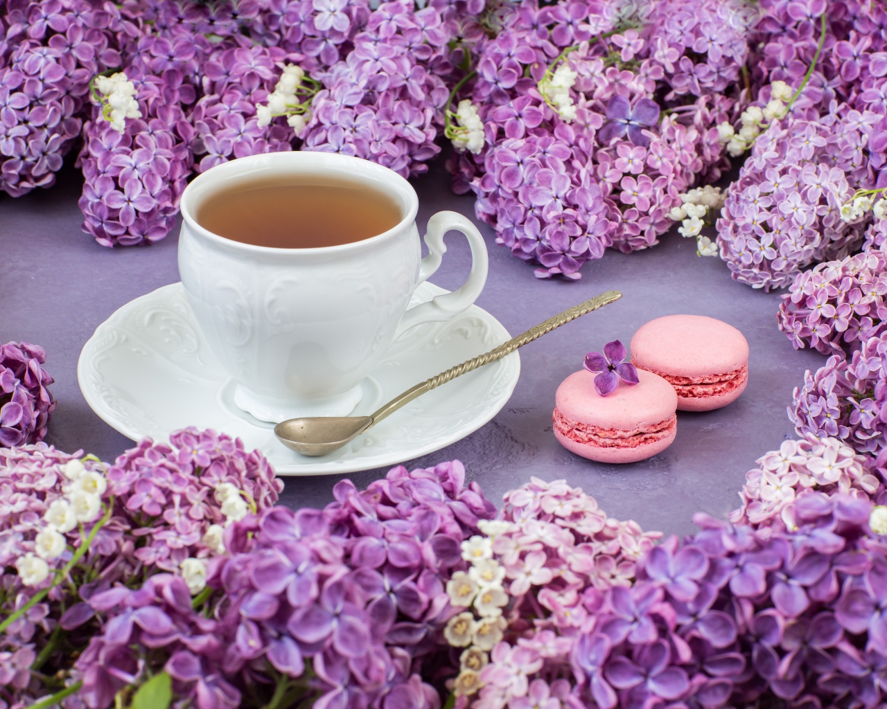 Чашка чая на столе с цветами сирени и десертом макарон
