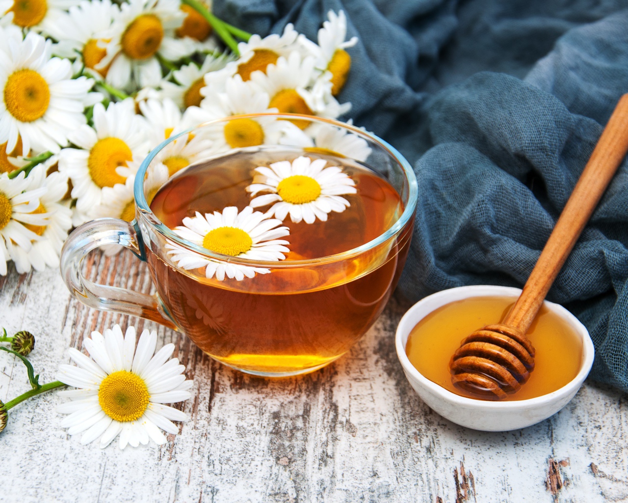 Чашка чая на столе с медом и букетом ромашек