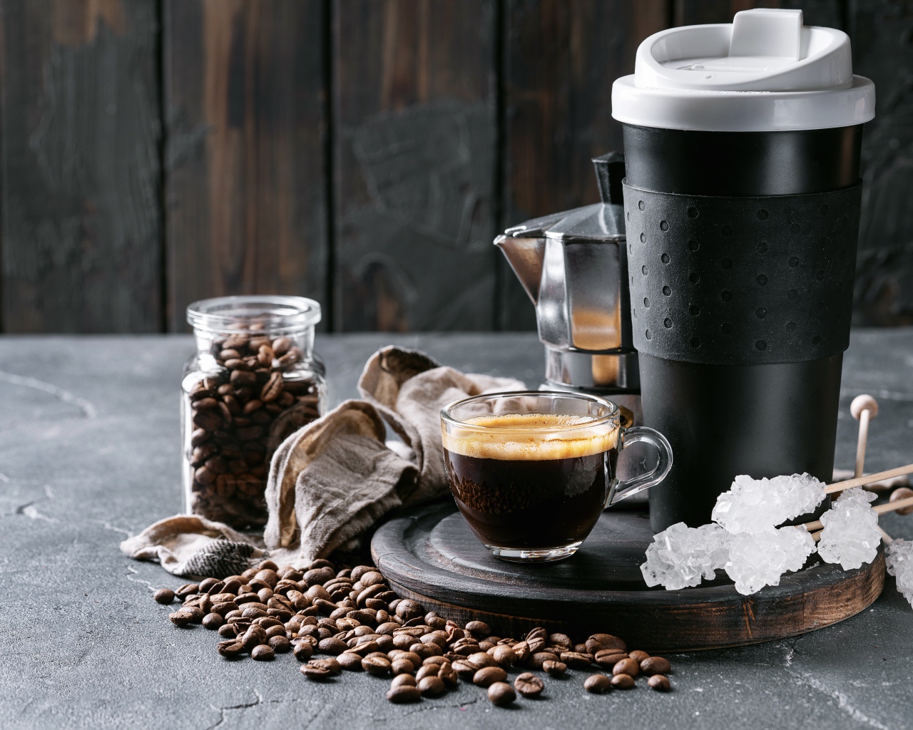 Стеклянная чашка кофе на столе с термосом и зернами