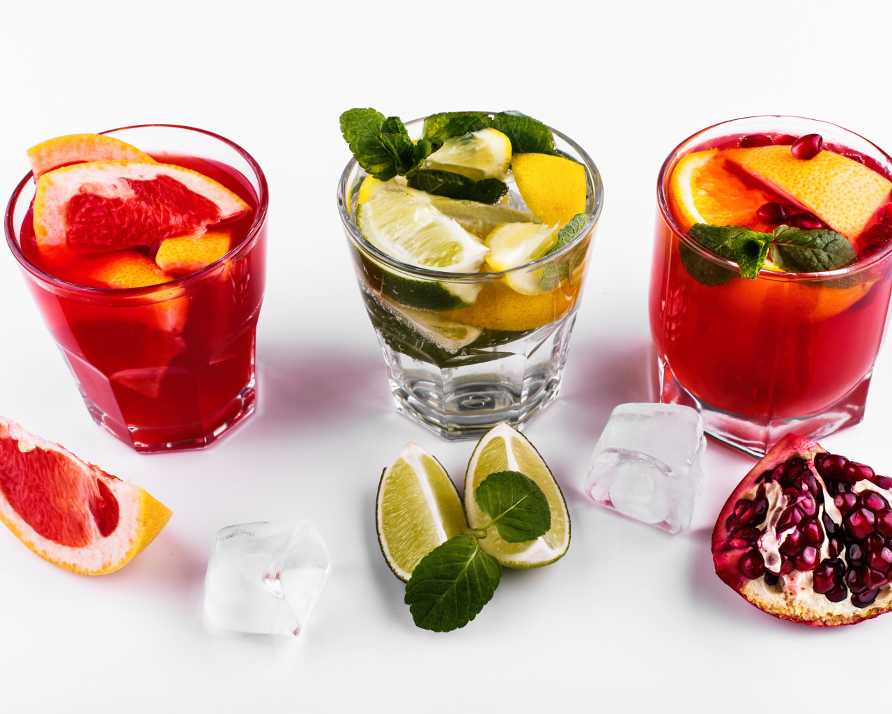 Стаканы с цитрусовыми коктейлями со льдом на белом фоне с фруктами