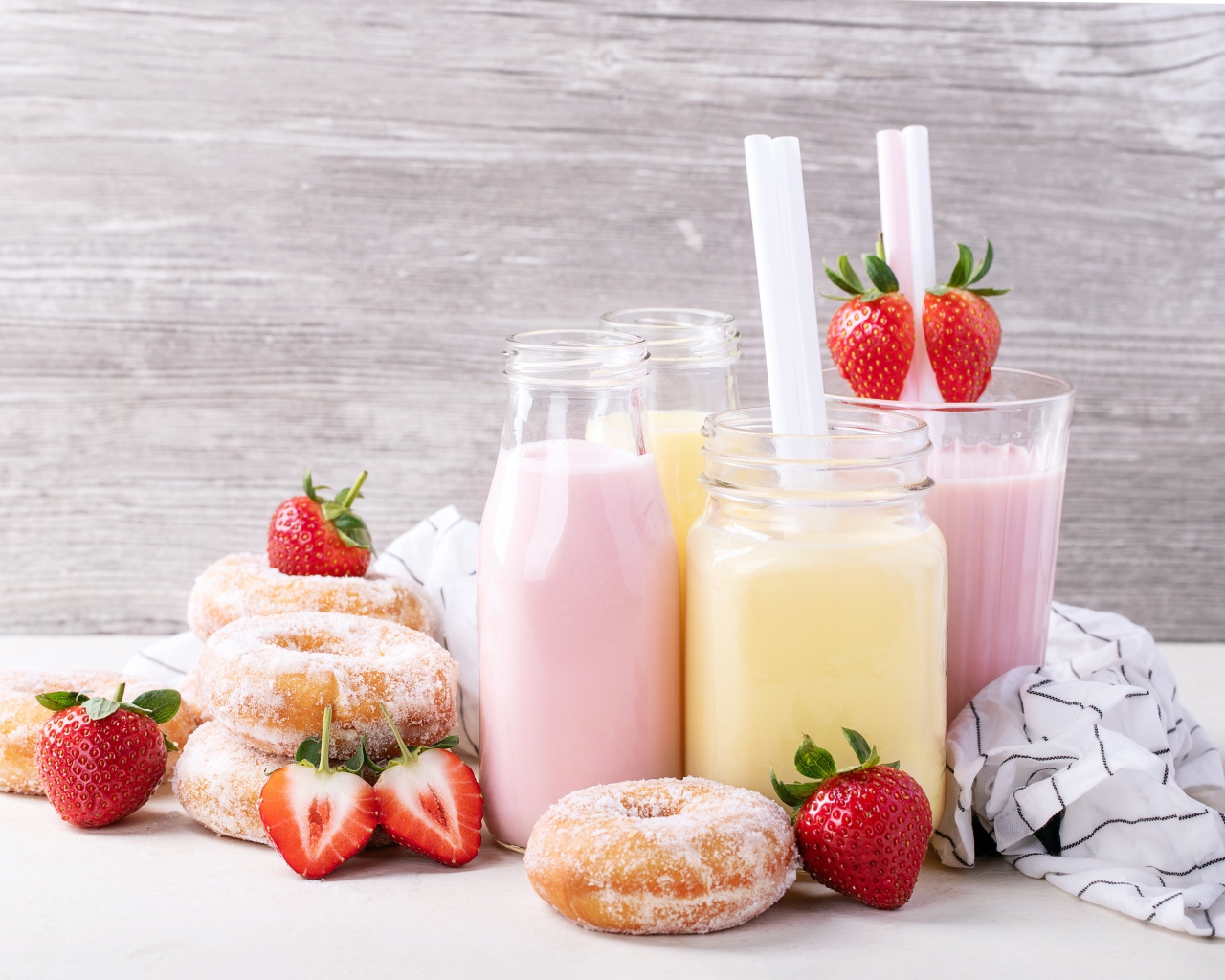 Молочные коктейли на столе с пончиками и ягодами клубники 