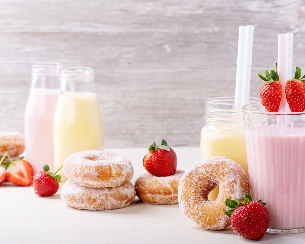 Молочные коктейли на столе с клубникой и пончиками