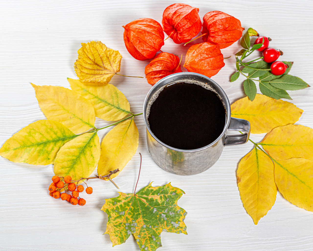 Кружка кофе на столе с осенними листьями, физалисом и шиповником
