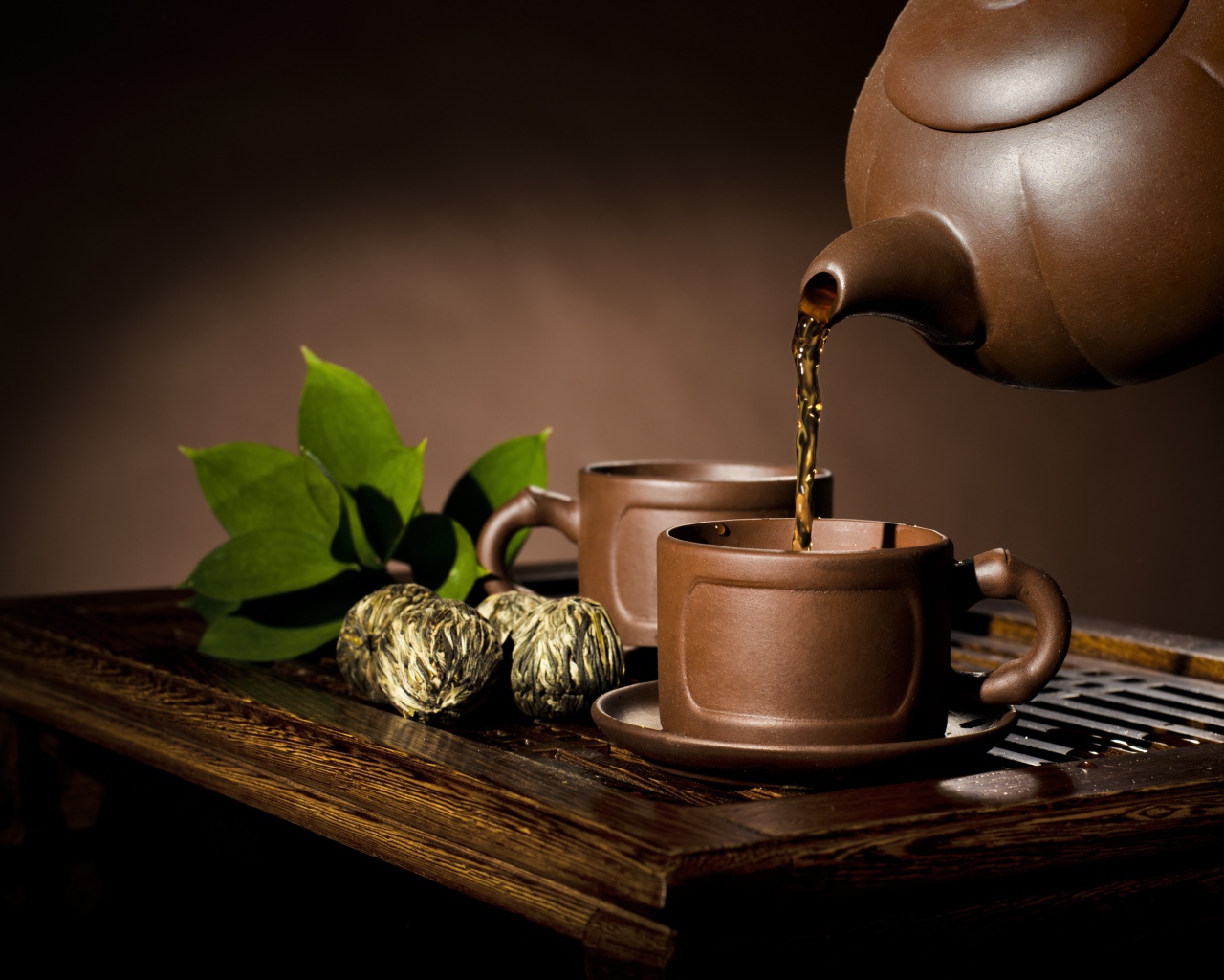 Чай наливают из чайника в коричневую чашку