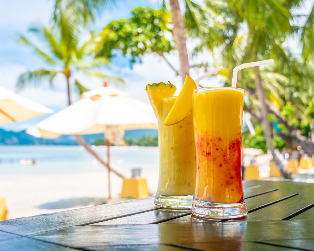 Два цитрусовых коктейля на столе на тропическом пляже