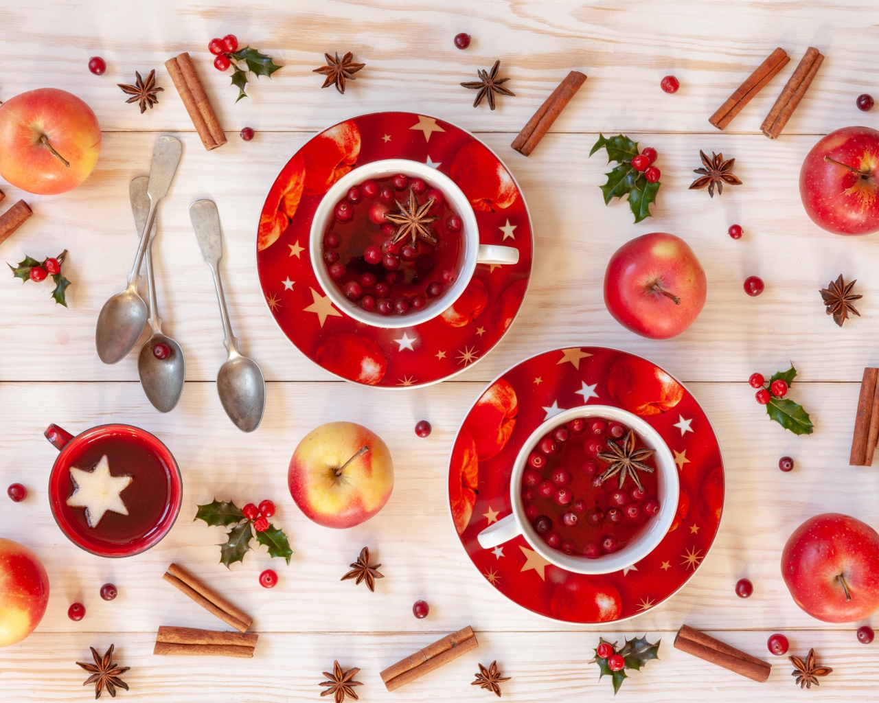 Две чашки клюквенного чая на столе с корицей, яблоками и бадьяном
