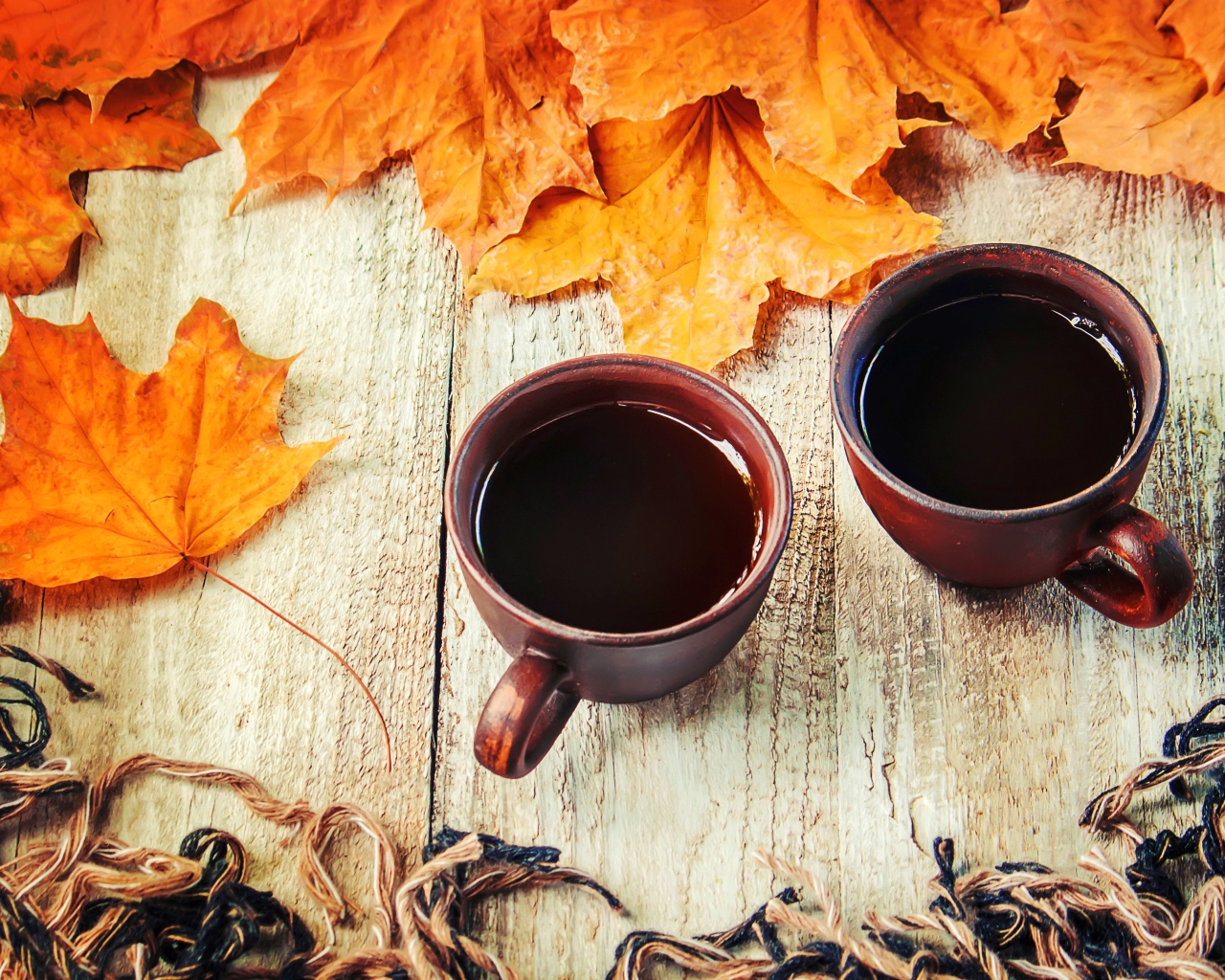 Две чашки горячего кофе на столе с сухими листьями