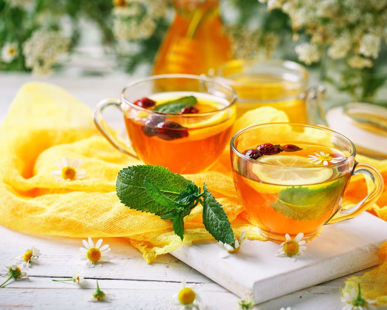Две стеклянные чашки чая с лимоном, мятой и шиповником
