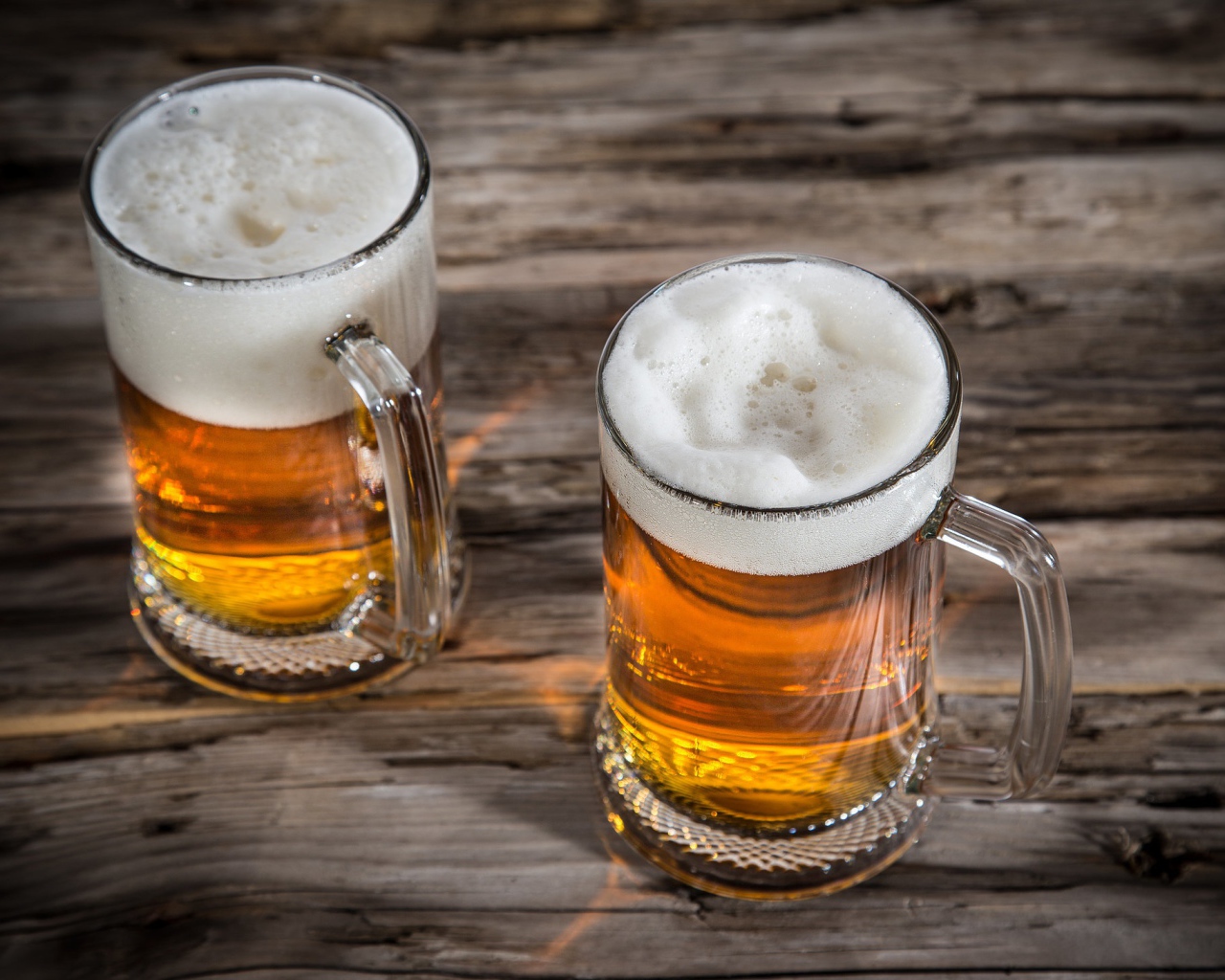 Два бокала пива с пеной на деревянном столе
