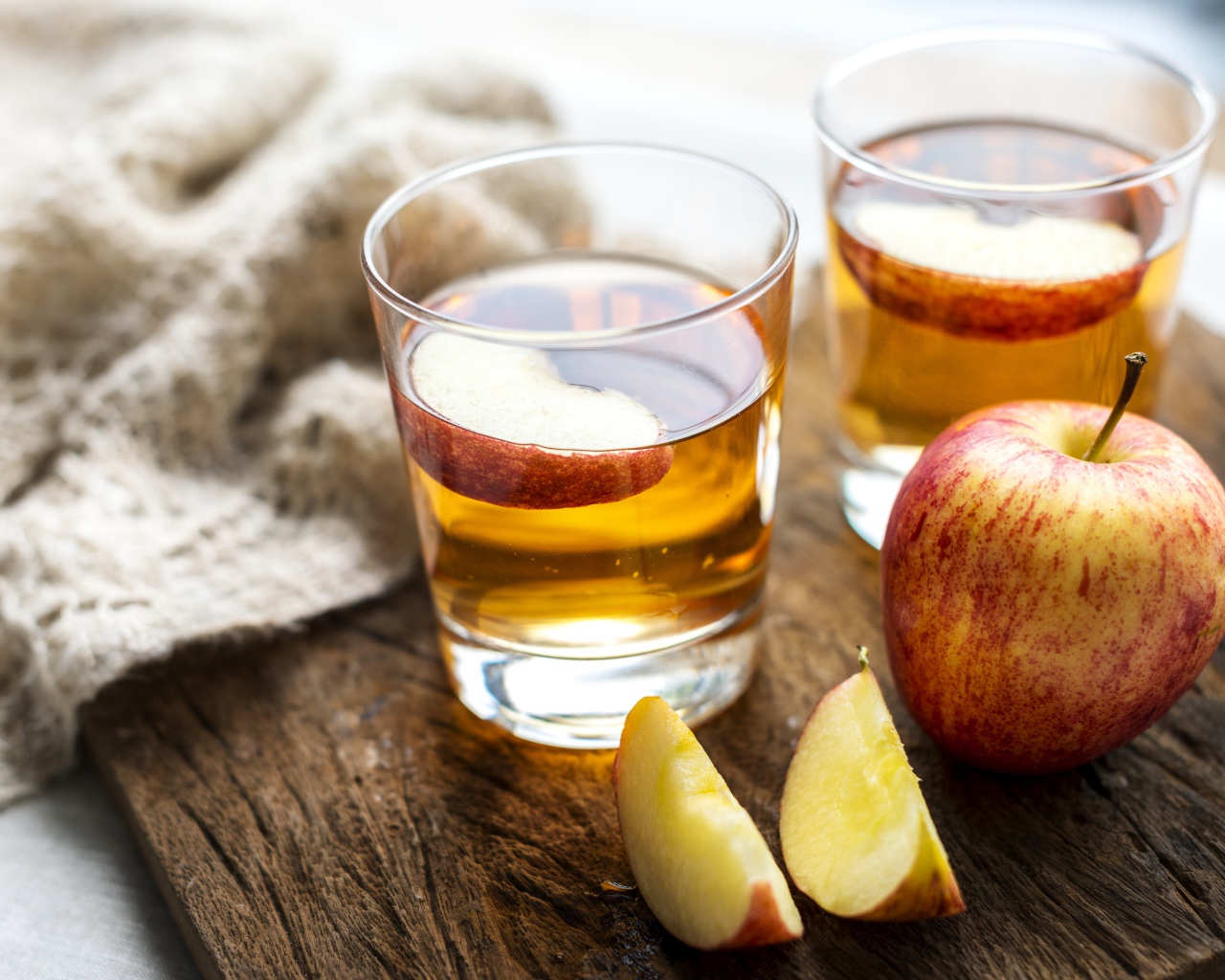 Два стакана сока на столе с яблоками 