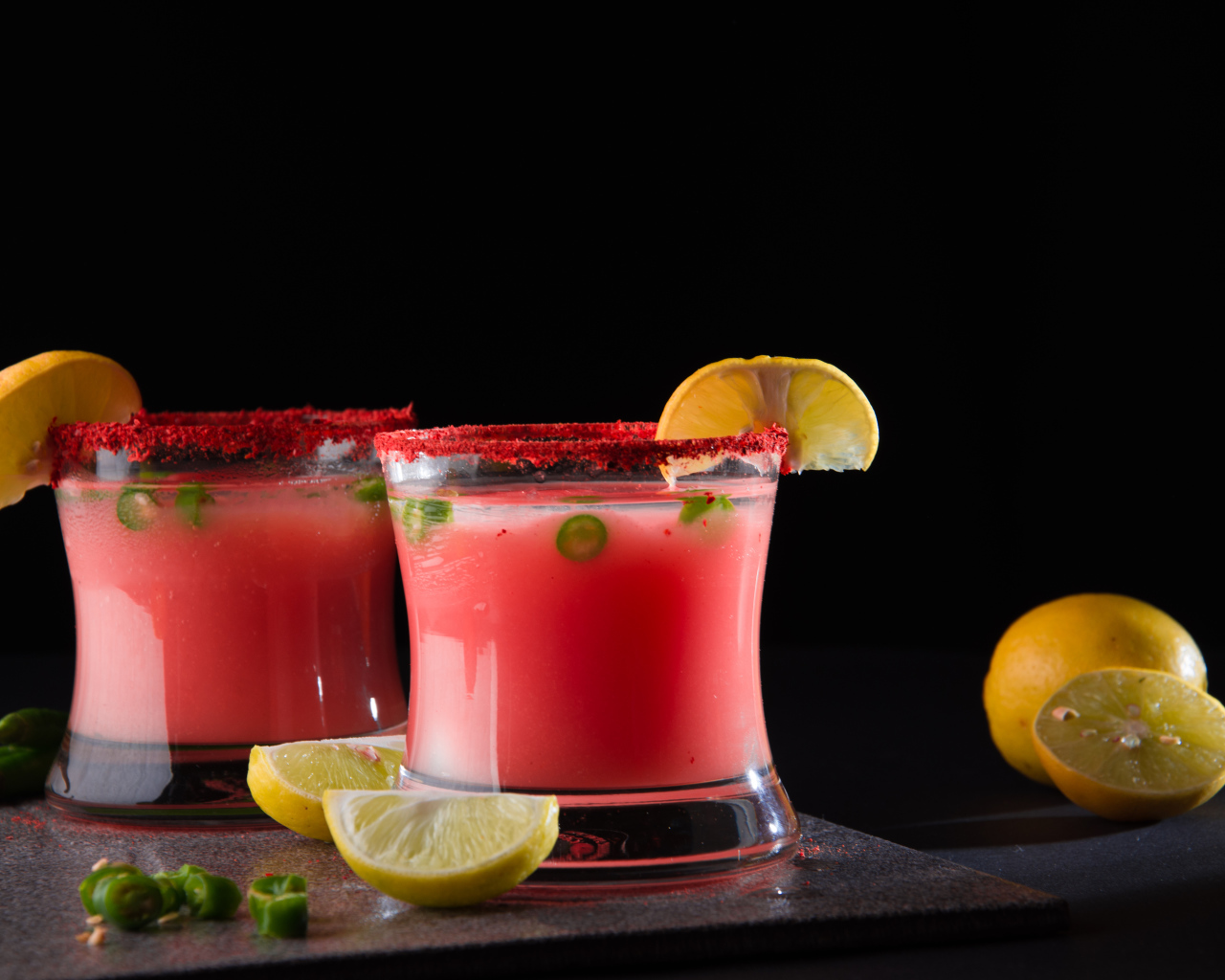 Два стакана с коктейлем на черном фоне с лимоном