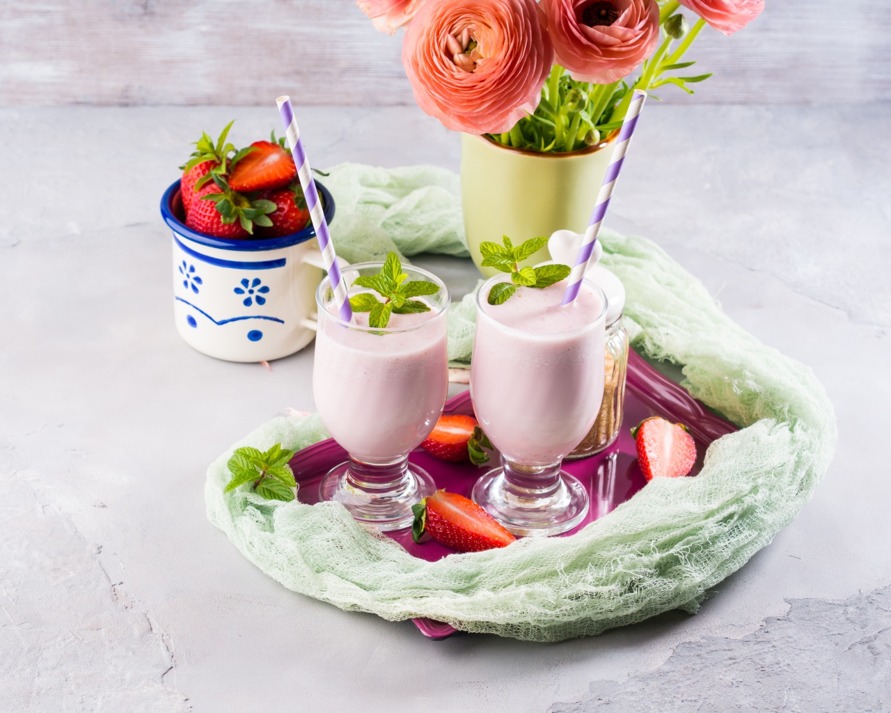 Два стакана с коктейлем на столе с букетом и клубникой