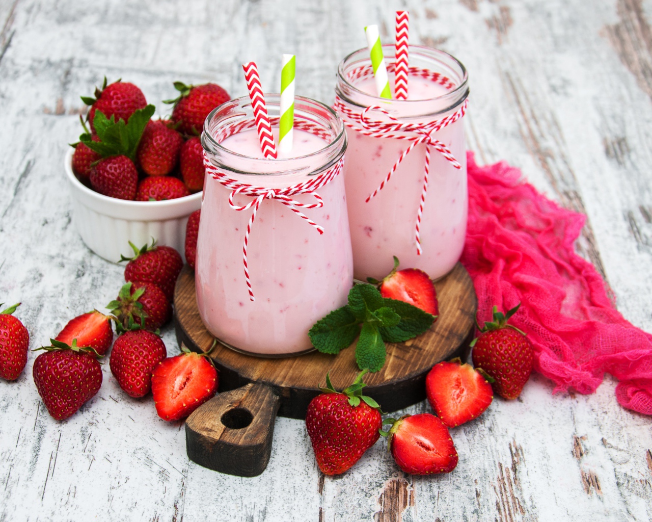 Две банки смузи стоят на доске на столе с клубникой