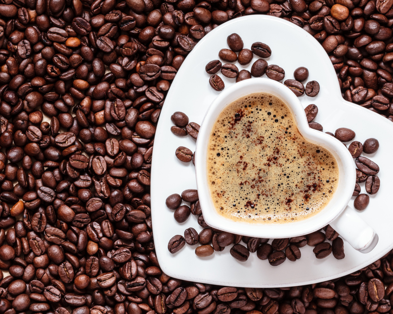 Белая чашка в форме сердца стоит на кофейных зернах 