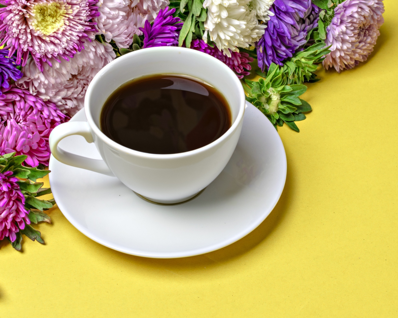 Белая чашка кофе на желтом фоне с букетом цветов астры