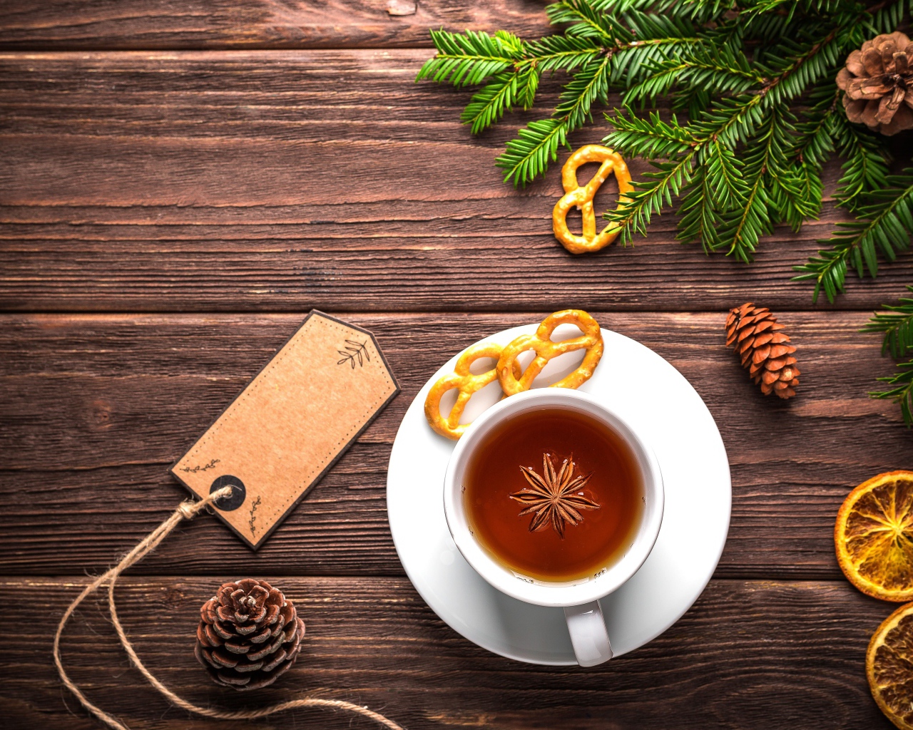 Белая чашка чая с бадьяном на деревянном фоне с веткой ели и сушеным апельсином
