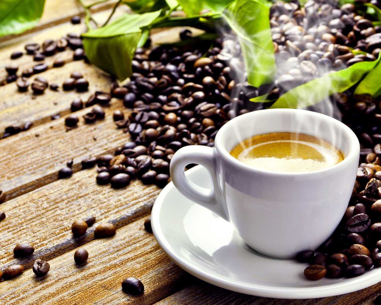 Белая чашка с горячим кофе на деревянном столе с кофейными зернами