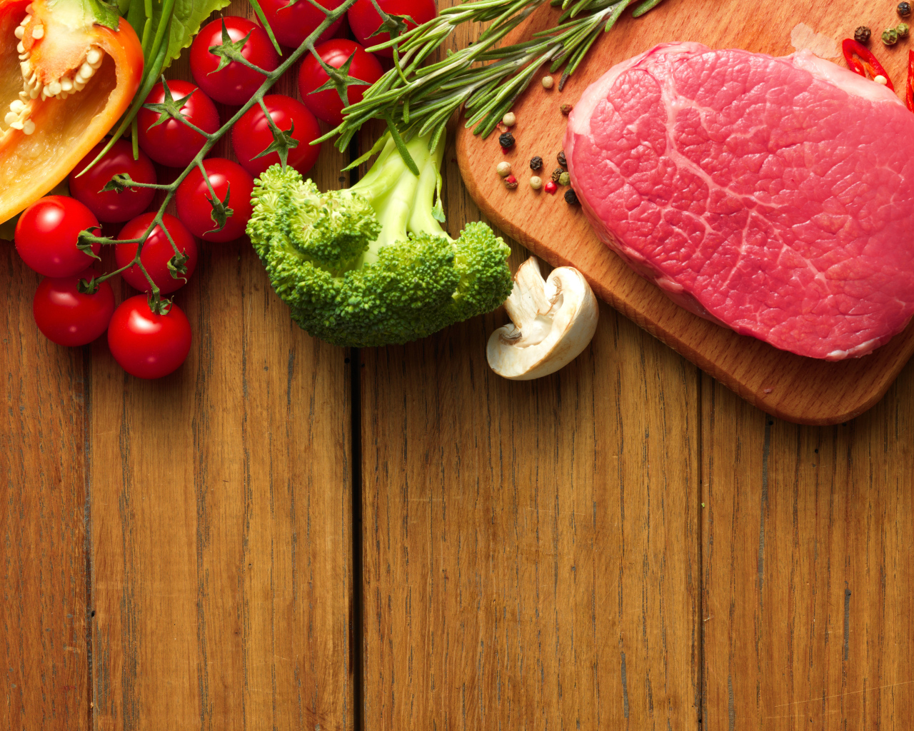 Кусок свежего мяса на столе с овощами и зеленью 