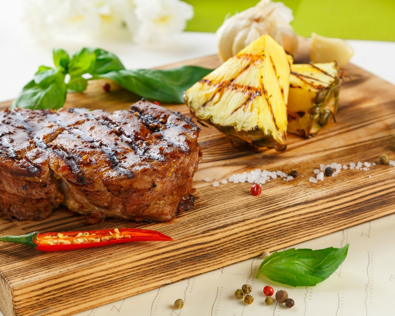 Кусок мяса гриль на деревянной доске с кусочками ананаса и базиликом