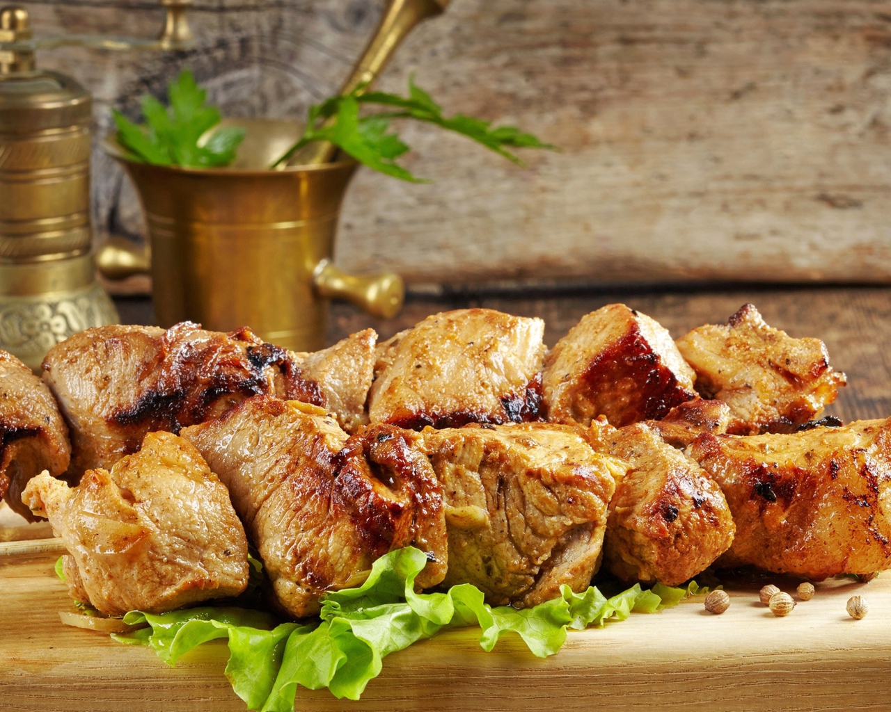 Аппетитный шашлык лежит на разделочной доске с листьями салата