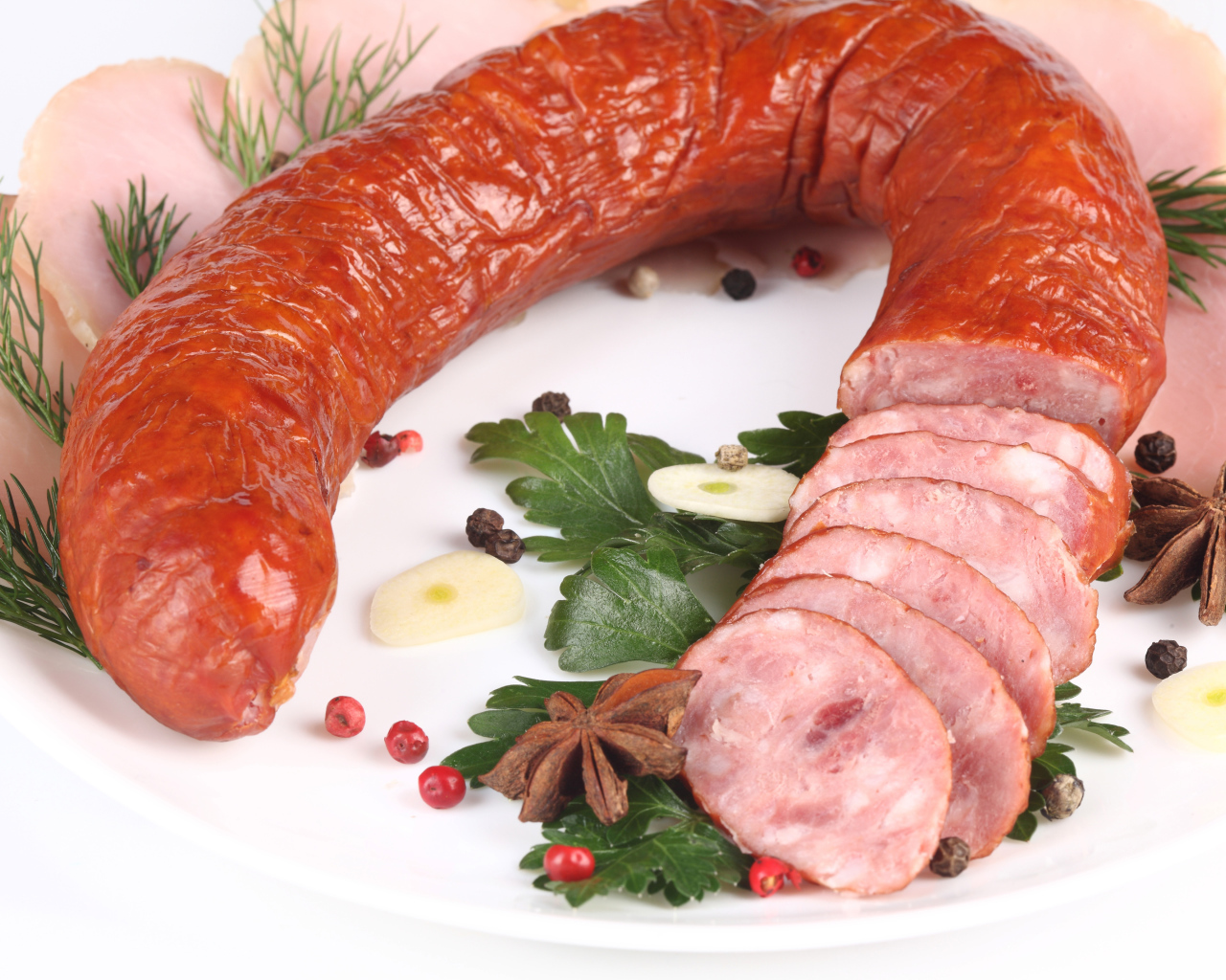 Аппетитная колбаса на белом фоне со специями и зеленью