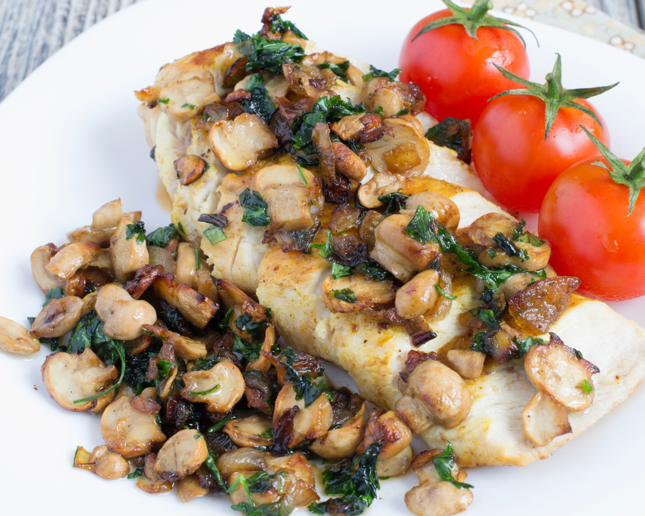 Аппетитный кусок куриного филе с грибами на тарелке с помидорами 