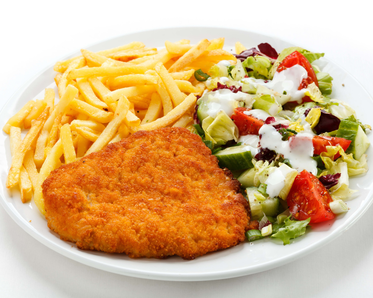 Отбивная с картофелем фри и салатом на большой белой тарелке