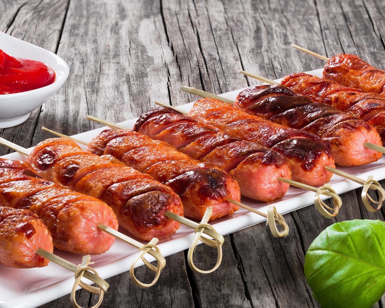 Сосиски гриль на шпажках на столе с соусом