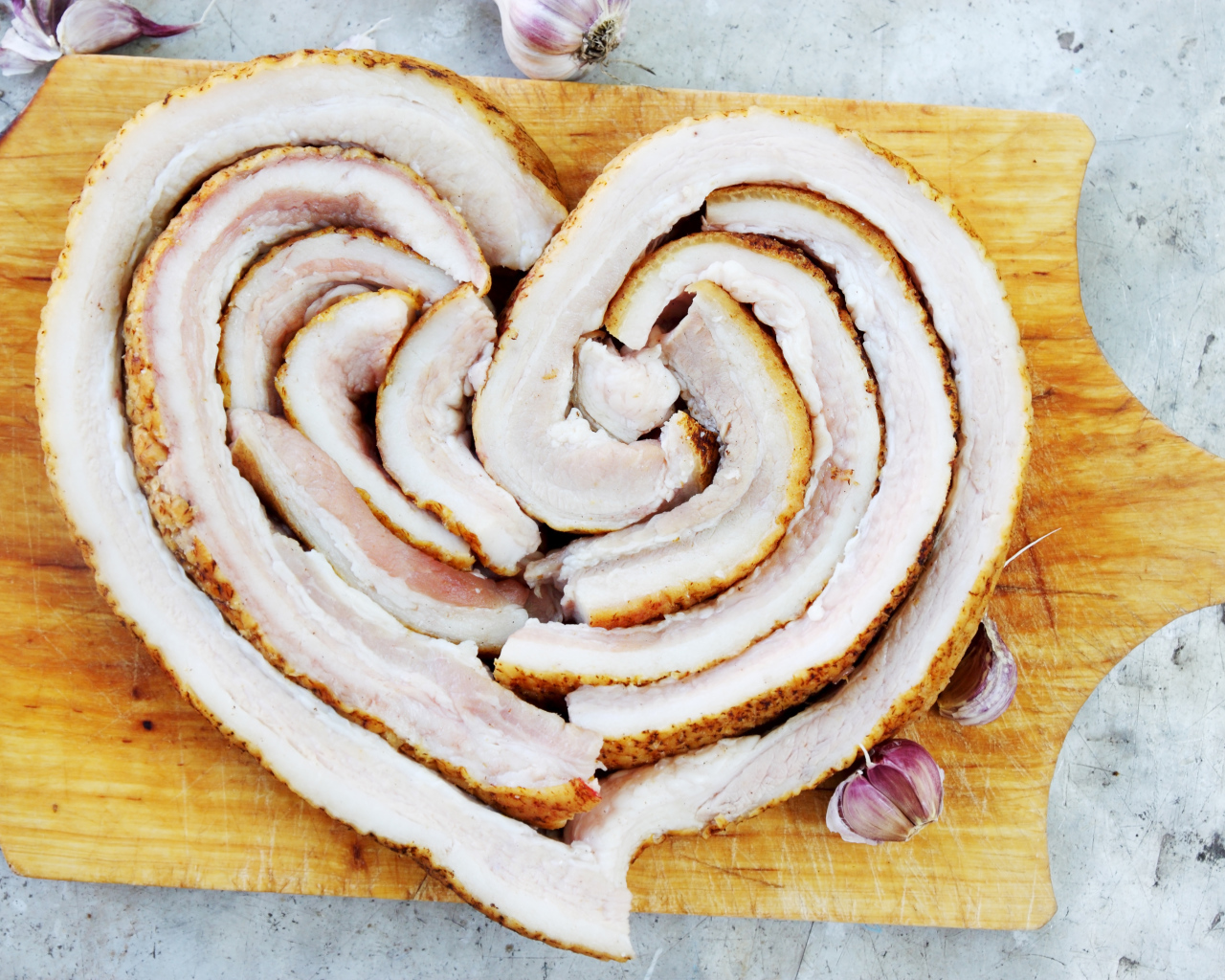 Сердце из свежего сала на доске с чесноком