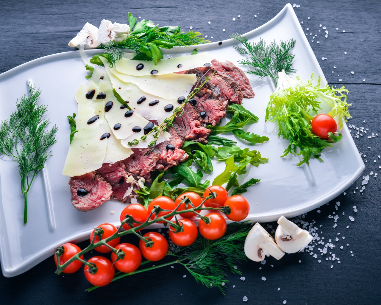 Мясо с сыром, овощами и зеленью на тарелке