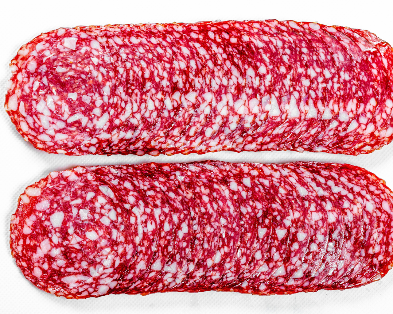 Колбаса салями нарезанная тонкими кусочками на белом фоне