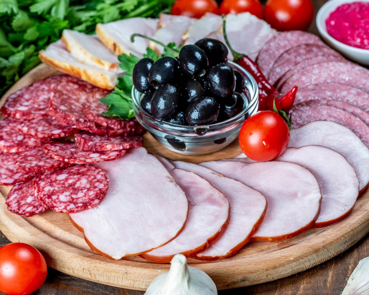 Колбасные продукты на доске с оливками