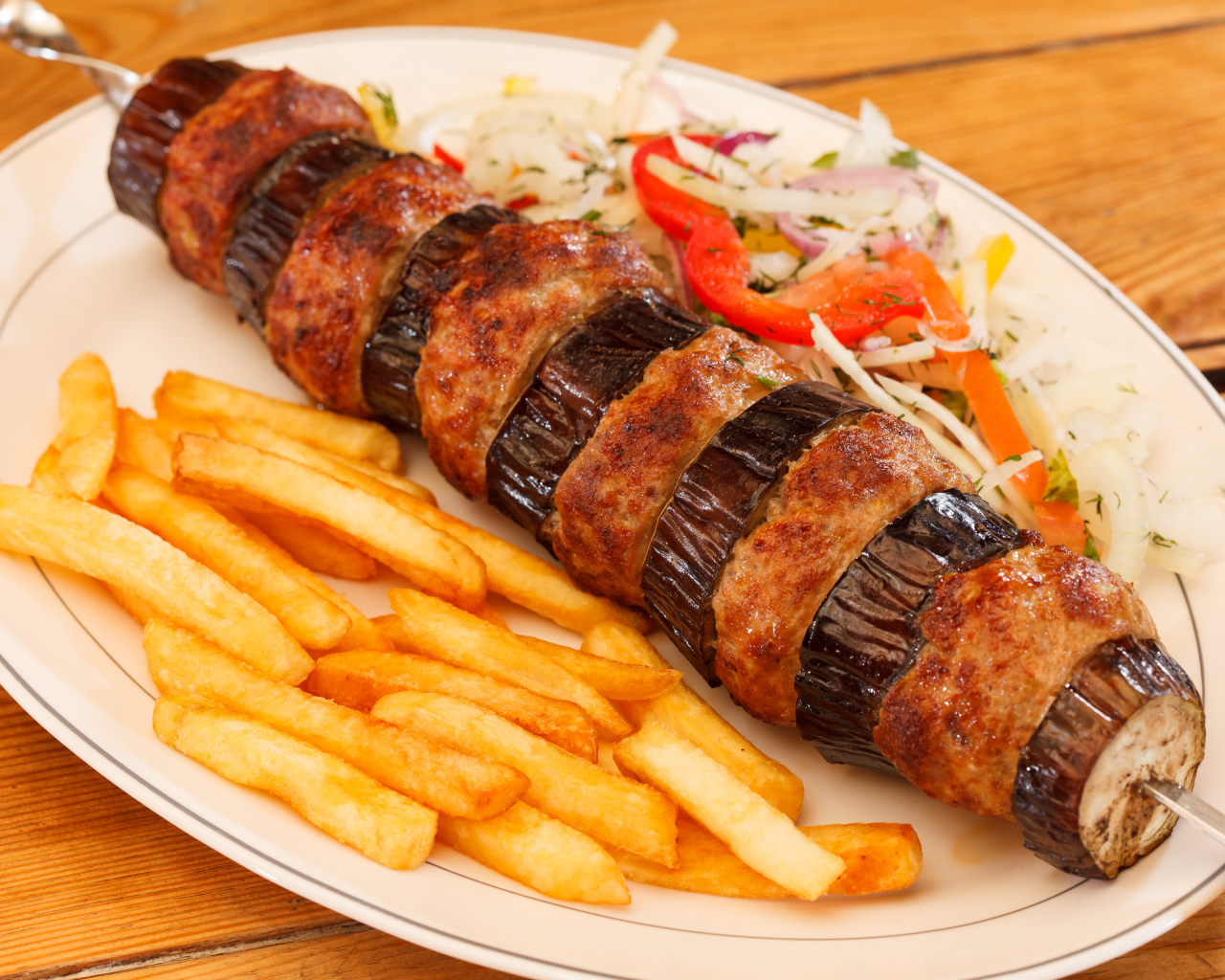 Шашлык с мясом и баклажанами на тарелке с картофелем фри 