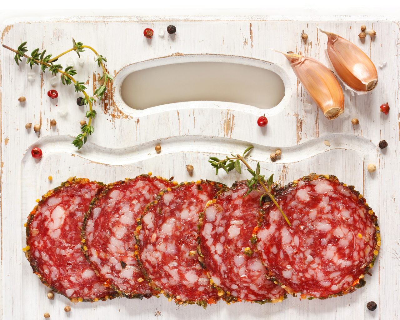 Нарезанная колбаса на разделочной доске со специями и чесноком