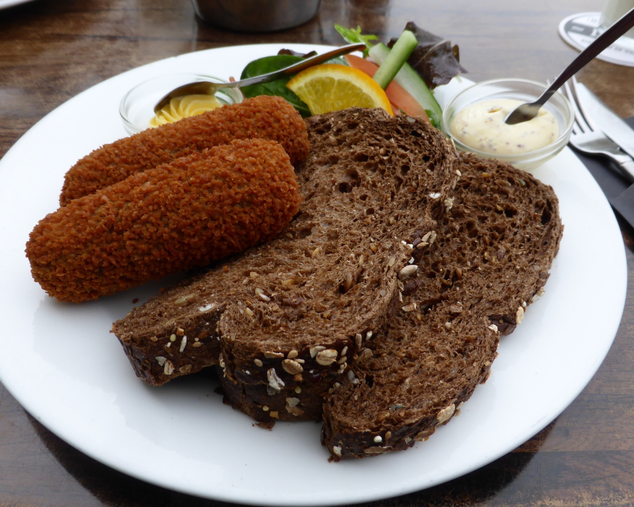 Два куска черного хлеба на тарелке с котлетами