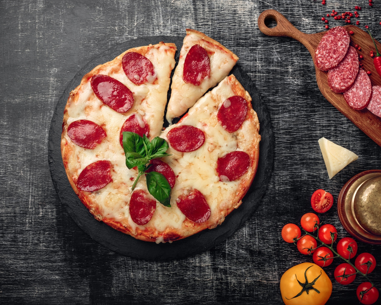Пицца с сыром и салями на столе с помидорами и колбасой