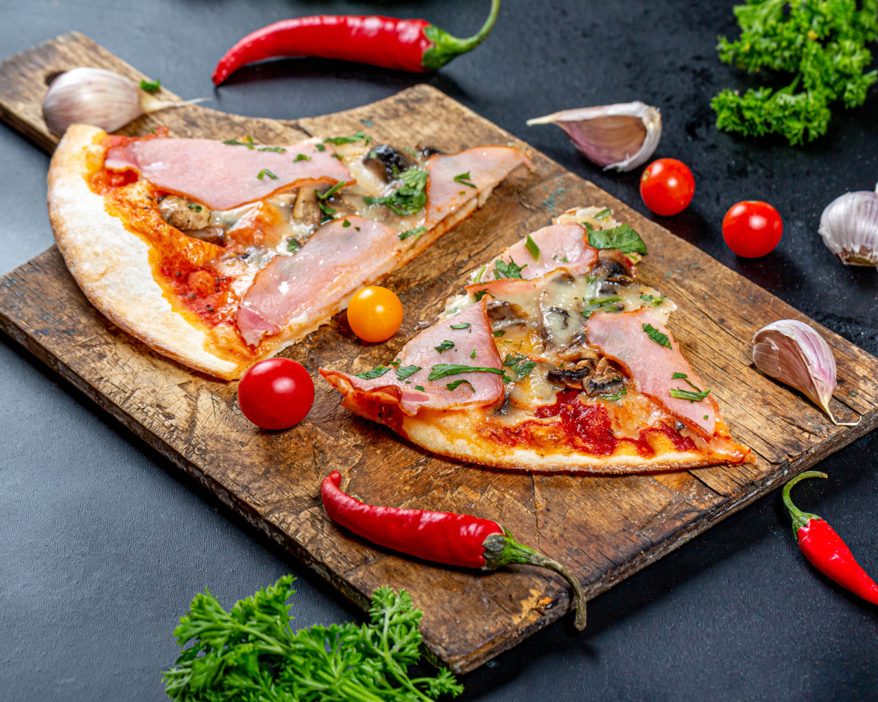 Два куска пиццы на разделочной доске с красным перцем и чесноком