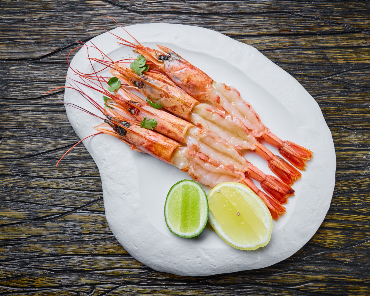 Аппетитные креветки на белой тарелке с лимоном